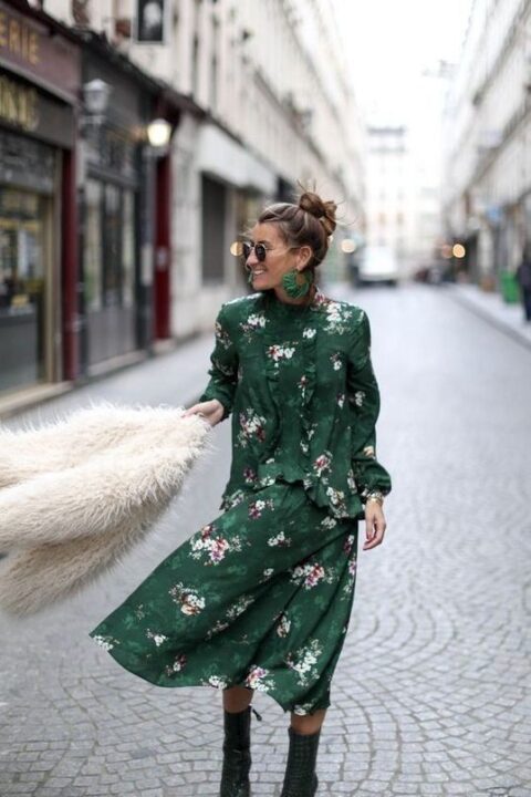 a beautiful and chic moody dark freen floral midi dress with long sleeves and ruffles, dark green heeled boots, green earrings and a faux fur jacket for a fall wedding