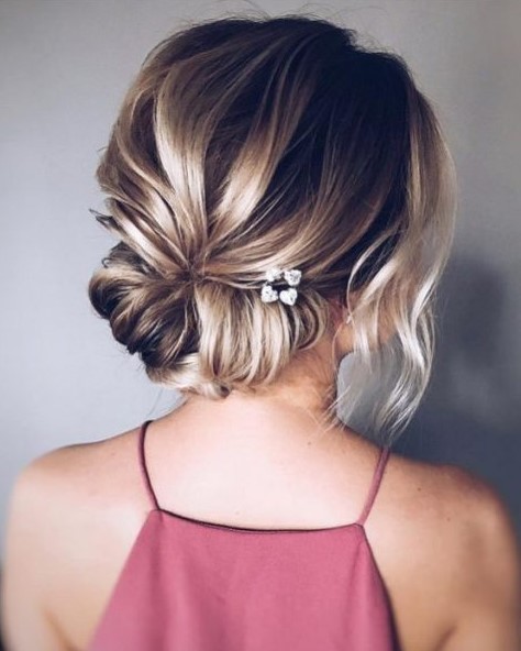 a casual wedding updo with a twisted low bun and a bump plus some locks down