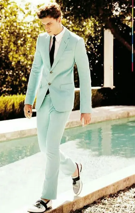 a mint green suit with a white shirt and a black tie and retro-inspired black and white moccasins for a spring groom