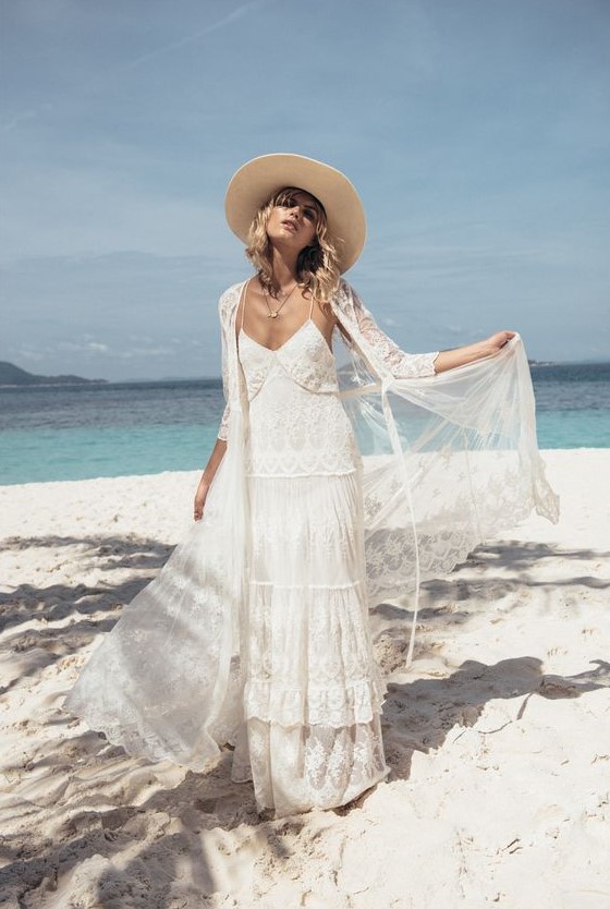 a boho lace spaghetti strap wedding gown with a matching coverup and a hat for a beach boho bride