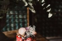 05 a buttercream wedding cake with red and chocolate drip, nuts, candies, macarons and dried grasses is super cool