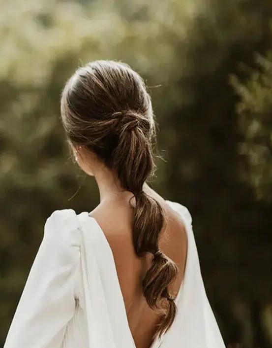 a cool low bubble ponytail with twists and a volume on top is a catchy idea for a classic bridal look