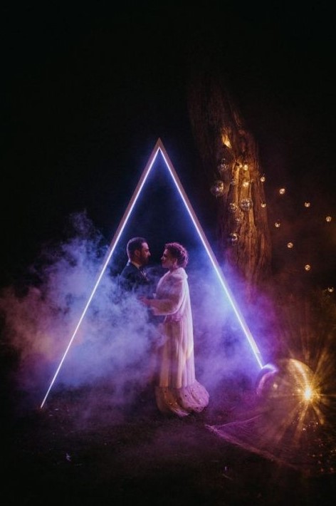 a fantastic neon geometric wedding arch looks just jaw-dropping, it's ideal for an evening or night ceremony and to take pics
