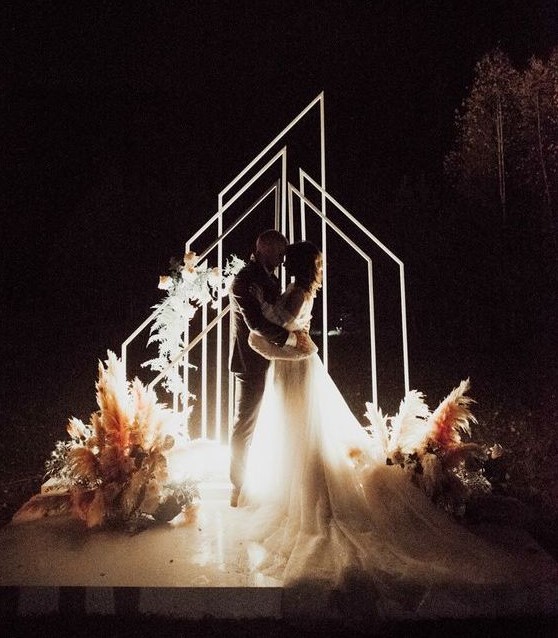 geometric LED arches and lights on the ground plus florals and pampas grass for a gorgeous night wedding ceremony