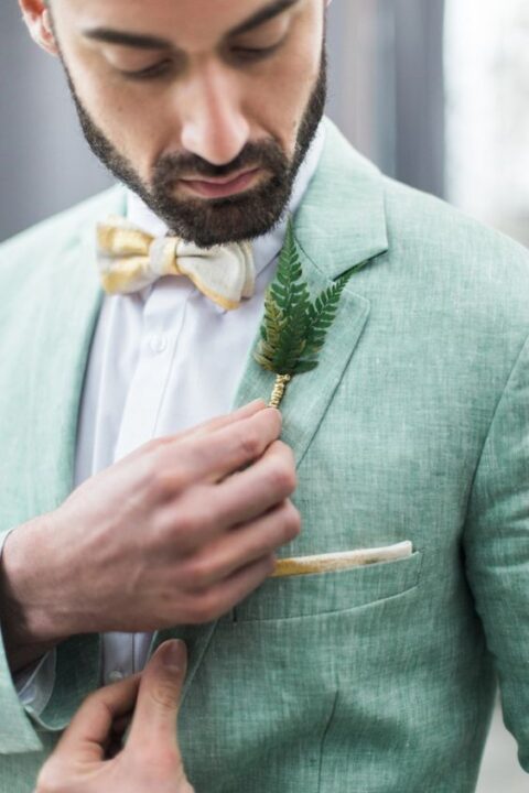a light green linen blazer with a yellow bow tie and a fern boutonniere for a woodland wedding