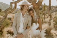 09 a groom wearing a tan and white windowpane suit, a white shirt and a hat, a bride wearing a plain wedding dress with side cutouts