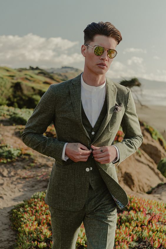 a modern to minimalist groom's look with a green three-piece pantsuit, a white shirt and sunglasses is a cool idea for a wedding