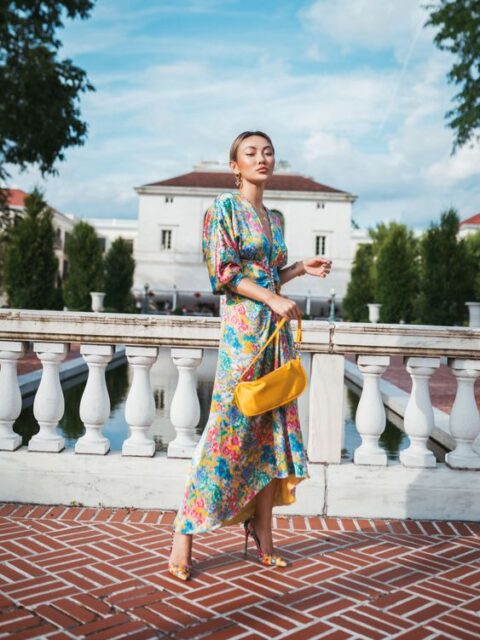 a bright summer wedding guest look with a colorful floral print midi dress with puff sleeves and a plunging neckline, matching shoes, a yellow bag
