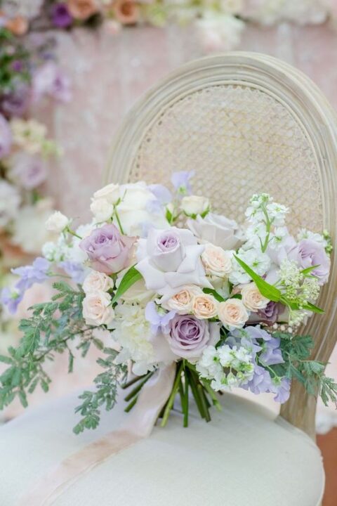 a chic and delicate wedding bouquet with lilac and blush roses, greenery and simple white blooms for a spring wedding