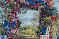 14 a super lush and bold floral wedding arch with blooming branches and flowers of all shades possible and with greenery