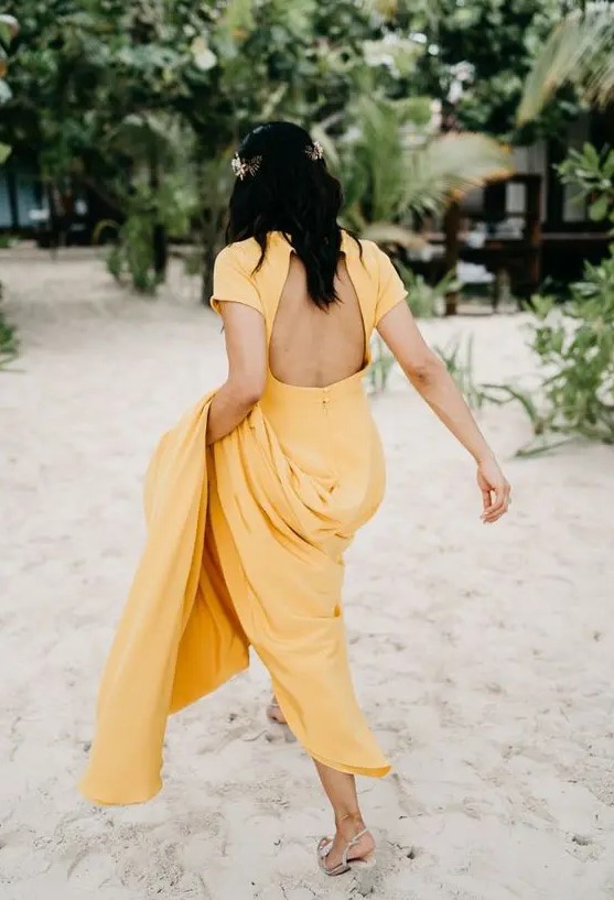 a yellow A-line wedding dress with a cutout back, short sleeves and a train for a tropical bride