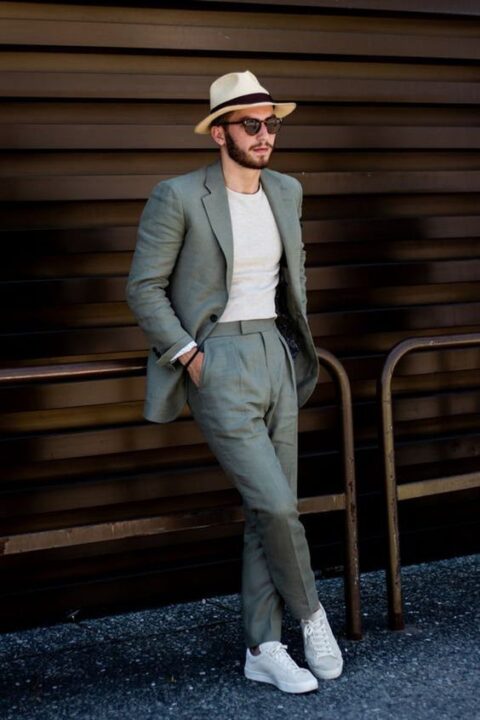 an informal summer wedding guest outfit with a grey pantsuit, a white fitting t-shirt, white sneakers and a hat