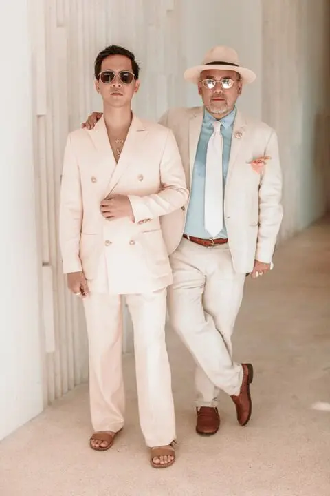 tropical wedding guest outfits, one with a creamy pantsuit and tan sandals, the second with a creamy suit, a blue shirt and creamy tie, a hat and brown loafers