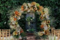 17 a bright round tropical wedding arch with tropical leaves, dried and spray painted ones, and fronds