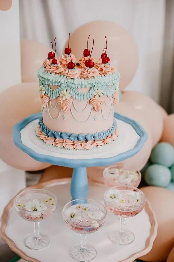 a pretty bright lambeth wedding cake done in pink, turquoise, blue, various sugar patterns and cherries placed on top