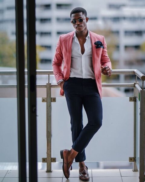 a bright tropical or summer wedding guest look with a white shirt, a pink blazer, navy pants and brown loafers