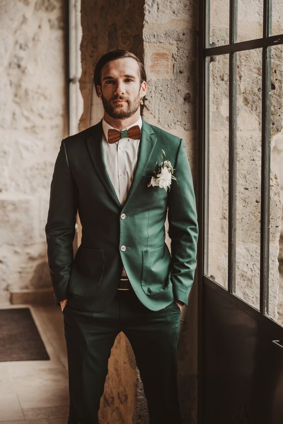 a cool green pantsuit, a white shirt, a brown and green bow tie and a lush white flower boutonniere are a lovely combo