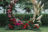 19 a lush round wedding arch with pampas grass, pink, blush, red and fuchsia blooms and tropical leaves