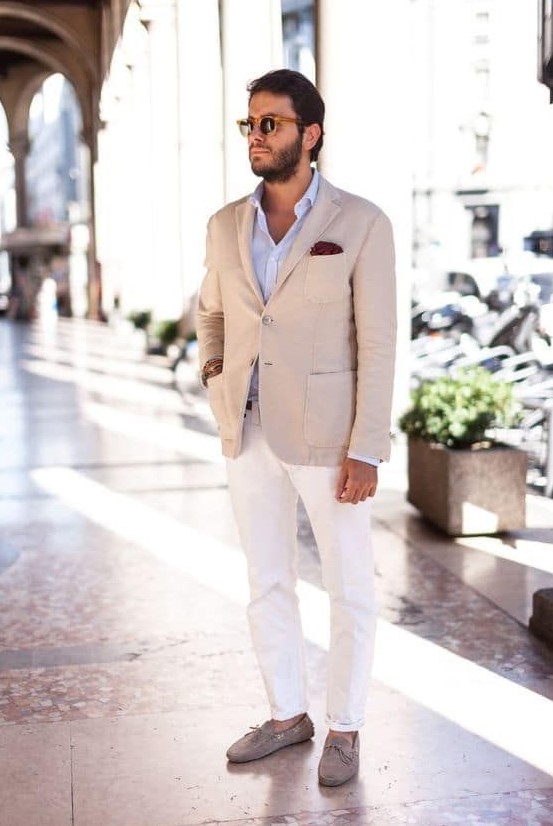 a chic look with a light blue shirt, a tan blazer, white pants, tan leather moccasins and sunglasses