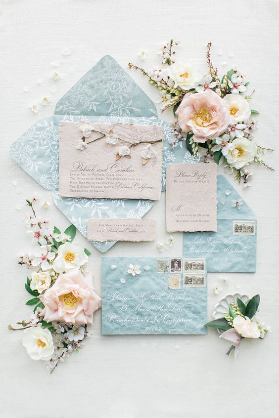 a lovely pasel blue wedding invitation suite with white floral prints and rough edge pieces is super cool