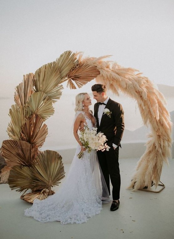 a round wedding arch partly covered with pampas gras and partly with dried fronds looks very cool and stylish