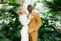 21 a groom wearing a mustard suit, a white shirt, a green bow tie and brown shoes looks super chic