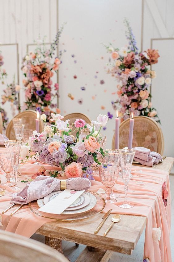 a lovely pastel wedding table setting with pink runners, pink, lilac and peachy pink blooms and lilac candles is amazing for spring