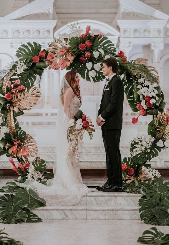 a bold round wedding arch with fronds, gilded fronds, white and pink blooms for a refined tropical wedding