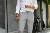 22 a relaxed outfit with a white shirt, grey thin stripe pants, white sneakers and sunglasses