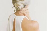 22 a twisted low bun with a volume on top and a statement hair pin for a minimalist bride