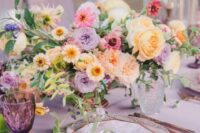 23 a lush pastel wedding tablescape with a lilac tablecloth, lilac, pink, peachy and purple blooms, purple glasses and printed placemats