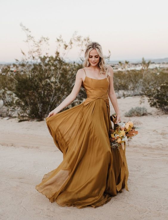 a chic mustard spaghetti strap wedding dress with a pleated skirt and a matching wedding bouquet are a great combo for a bride