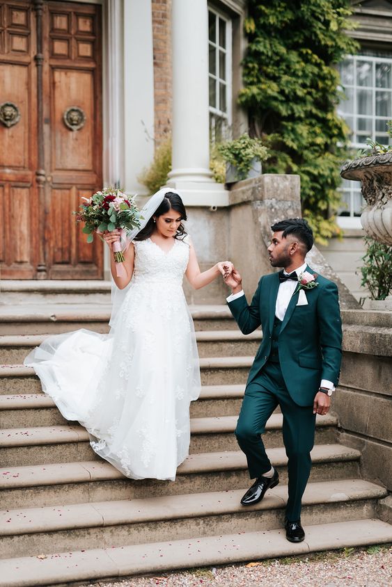 a dark green three piece pantsuit, a white shirt, a black bow tie and black shoes compose a super elegant wedding outfit