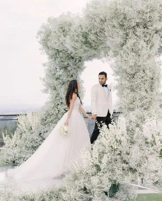 a jaw-dropping wedding arch that feels like a cloud as it's fully covered with white baby's breath is amazing