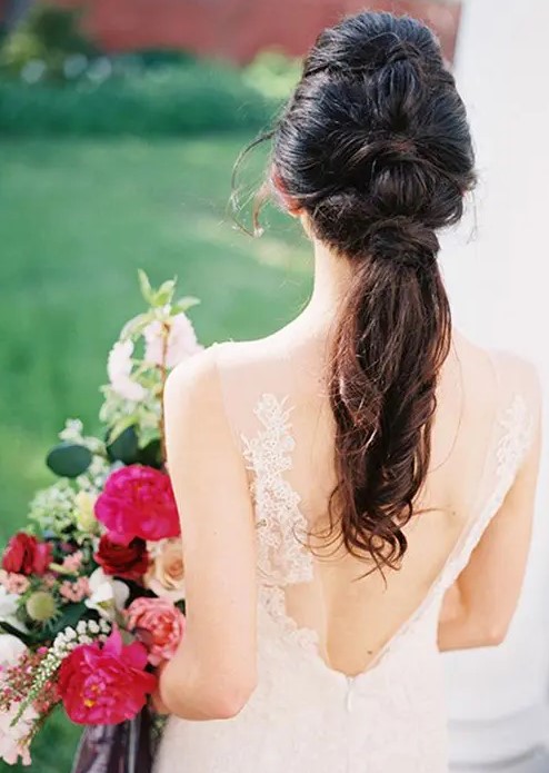 a stylish modern wedding ponytail with some twists coming from top to the bottom and a volume on top