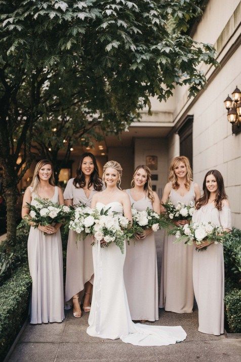 a bride wearing a strapless mermaid wedding dress with a train, bridesmaids rocking mismatching neutral maxi dresses