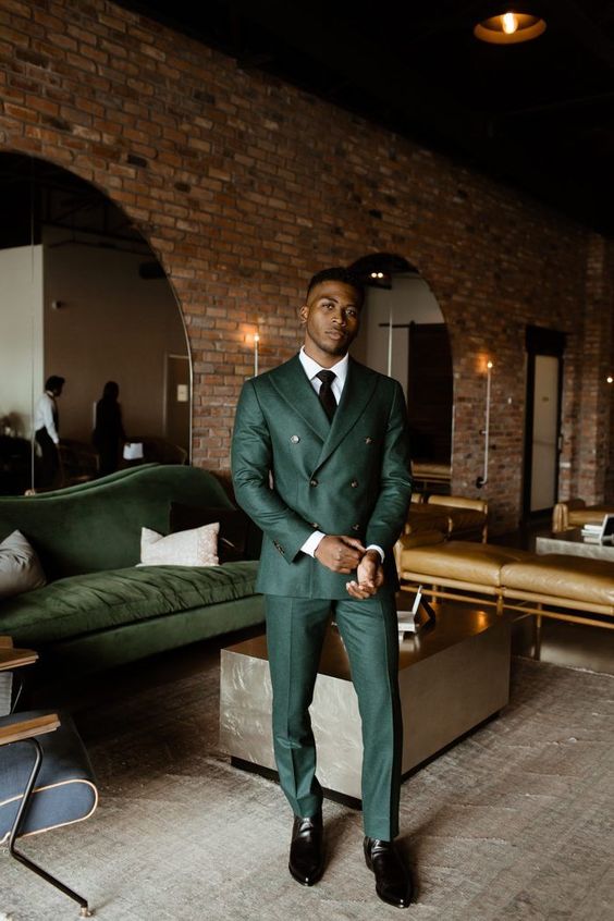a green pantsuit with a double breasted blazer, black shoes, a white shirt and a black tie are a lovely combo for a fall wedding