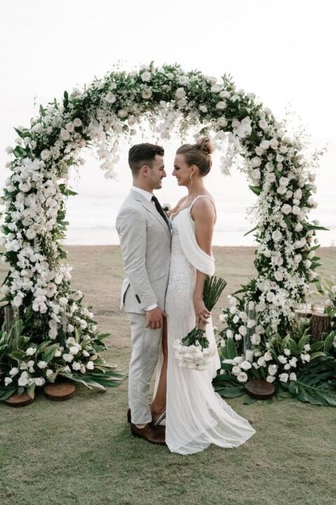 a beautiful round wedding arch with greenery and lush white blooms is a perfect solution for a summer wedding
