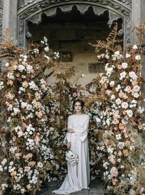 a breathtaking fall wedding backdrop of dried leaves, neutral blooms in blush and white is a gorgeous solution to rock