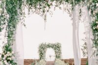 28 a blooming elegant ceremony space with super lush white florals and greenery and some touches of light blue is a great idea for summer