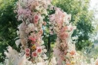 29 a fantastic and super lush wedding arch with pink, yellow and orange blooms and blooming branches plus pink baby’s breath all over