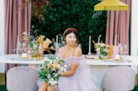 29 a pastel wedding reception space with yellow pendant lamps, pastel blooms and pampas grass, the bride wearing a lilac dress and shoes
