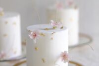 29 a white buttercream wedding cake with gold leaf and pink cherry blossom is a chic and cool idea for a spring wedding