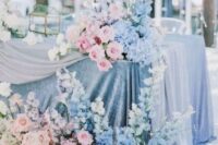 30 a pastel wedding tablescape with blue tablecloths and runners, pink, lilac and blue blooms and lights for a magical spring wedding