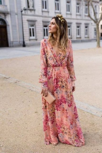 a pink floral maxi dress with a deep V-neckline and long sleeves, a blush clutch and a gold headband for a summer wedding