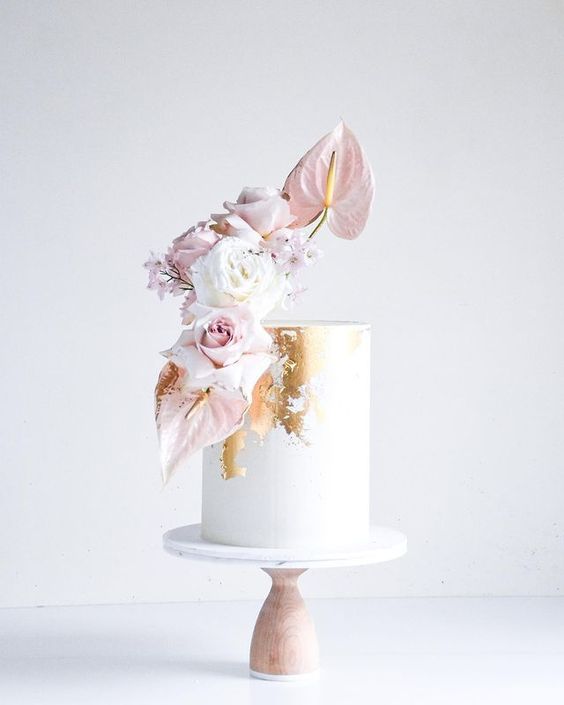 a white buttercream wedding cake with gold leaf, white and blush roses and other blooms is a stylish and bold idea for a formal wedding