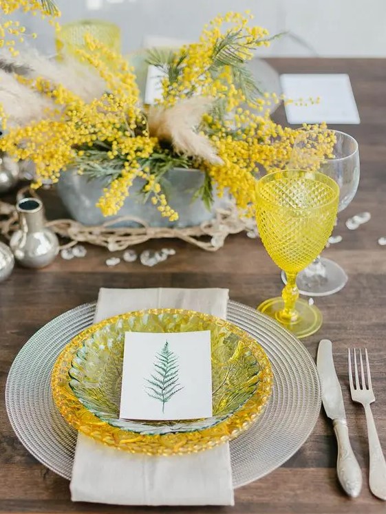 a bold spring wedding tablescape with mimosa blooms, a yellow and green plate, a yellow glass and crystals