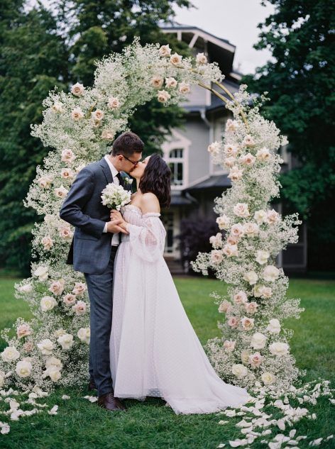 a delicate and beautiful wedding arch covered with white baby’s breath and blush and white roses is a romantic idea for a spring or summer wedding