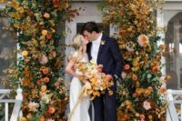 31 a refined and cool modern fall wedding arch composed of bold rust, yellow, mustard blooms and greenery and bright fall leaves