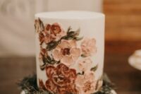 31 a white buttercream wedding cake with painted blush and rust blooms and greenery around the cake for a boho wedding